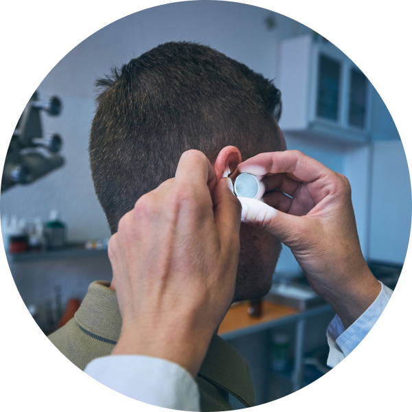 A doctor is examining the ear of a patient with tools and flashlight.
