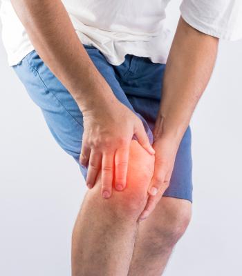 A man in pain is clutching his knees, with the affected area highlighted in red.