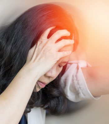 A woman holding her head shows signs of pain.